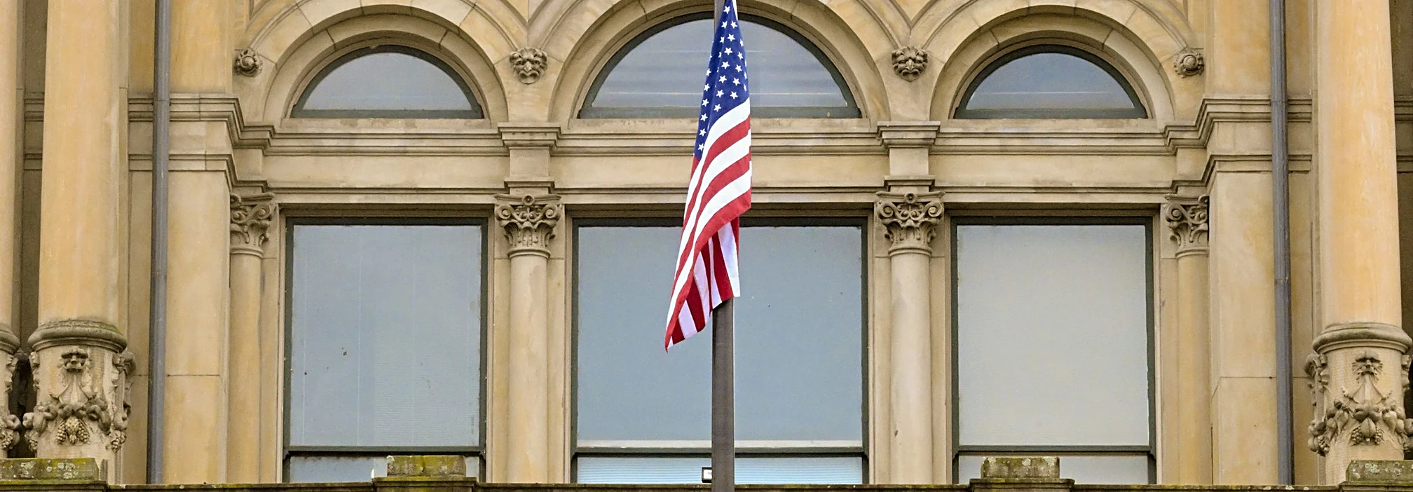 Neoclassical courthouse columns with an American flag in bright daylight